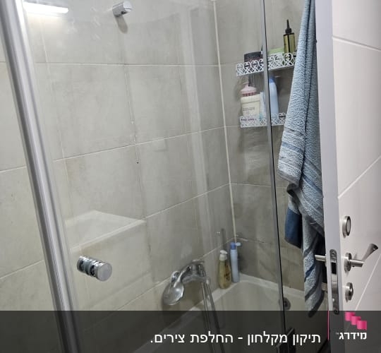 מקלחת עם דלת זכוכית ומגבת תלויה